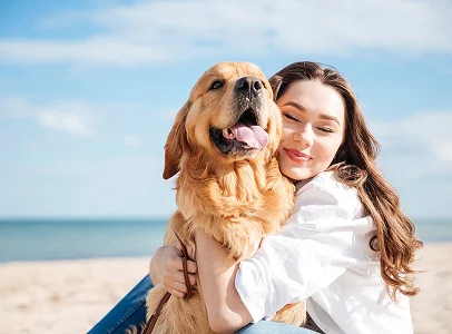 Femme souriante serrant un golden retriever sur une plage ensoleillée à Montgiscard en Haute-Garonne 31