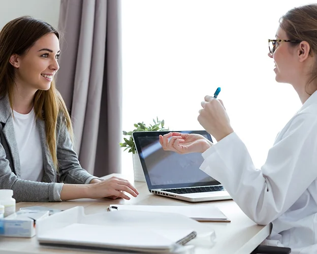 Médecin en blouse blanche discutant avec une patiente souriante dans un cabinet médical à Montargis en Haute-Garonne 31